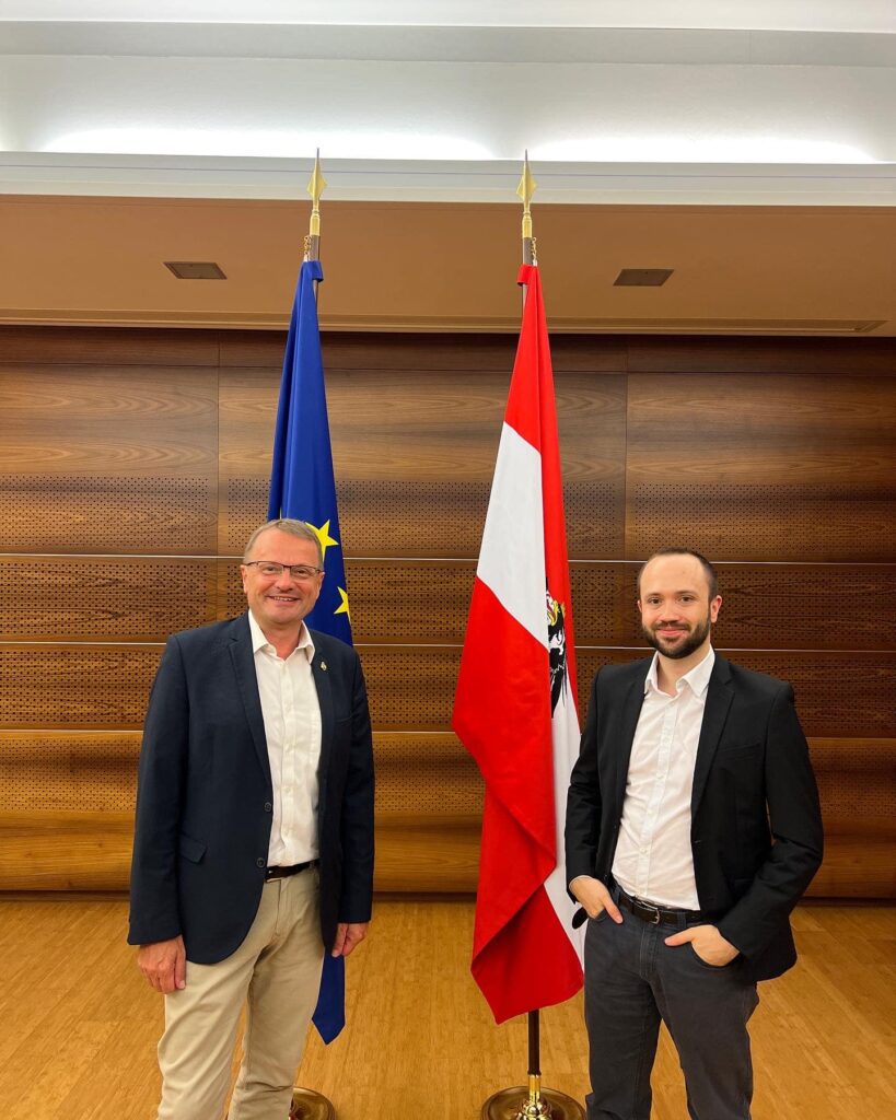 Bilan Politique d’Août 2024 – La France en Pleine Tourmente Institutionnelle Andreas Eisl (à droite) est un chercheur politique explique que l'incertitude politique du mois d'août a des retombées économiques non-négligeables.