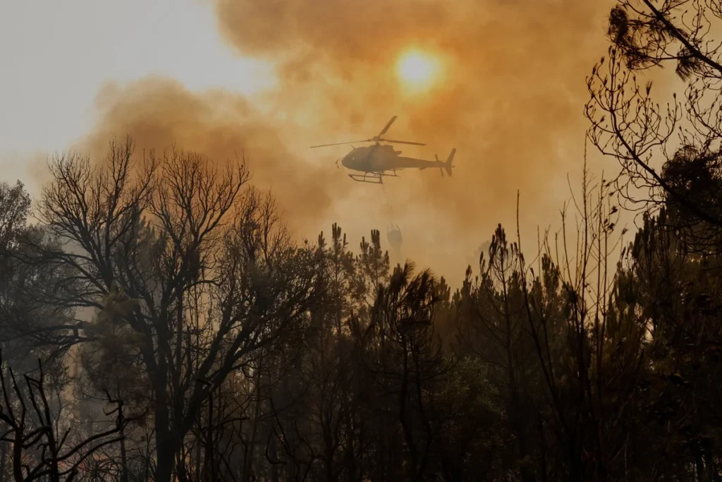 Un hélicoptère qui plane au-dessus d'une forêt en proie à un incendie en Espagne.