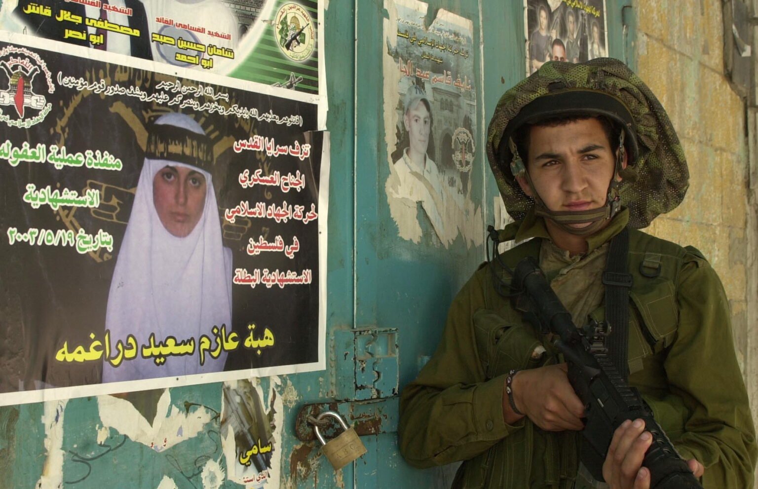 Un soldat israélien à côté d'une affichache du Jihad islamique qui promeut les attentats-suicides.